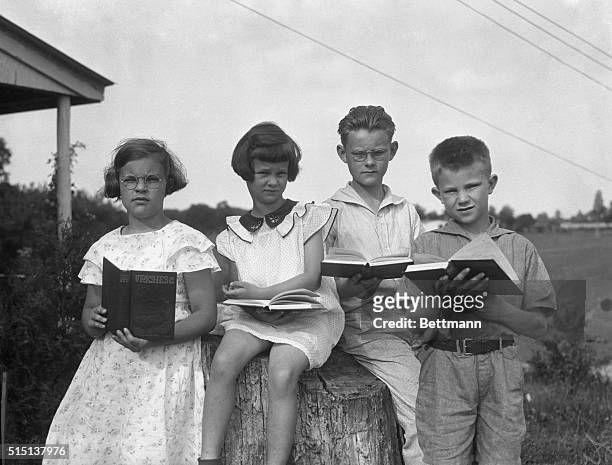 Jehovah's Witness children reading books outdoors.