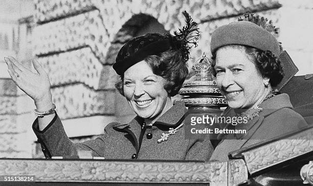 London: H. M. Queen Beatrix of the Netherlands waves to the crowd as she rides in an open carriage with H. M. Queen Elizabeth II past Horse Guards...