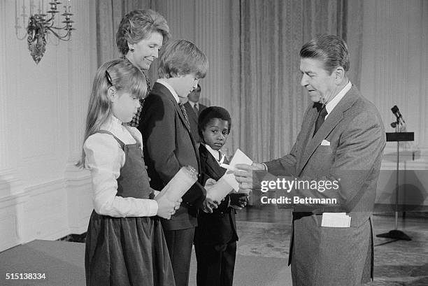 Washington: President Reagan lights symbolic candles to be used at dusk at school prayer day festivities as Nancy looks on. L-R are C. Messing of...