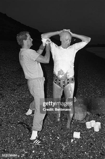 Dover, England: Dr. James Counsilman the famed swimming coach of Indiana University, being greased prior entering the water at Shakespeare Beach...