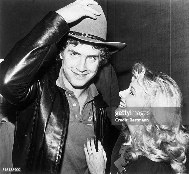 Lori Ogden a TCU cheerleader from Fort Worth, helps Pittsburgh Panther quarterback Dan Marino put his cowboy hat on compliments of the Cotton Bowl...