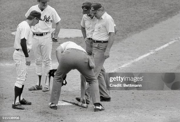 Umpire Tim McClelland measures the pine tar on Royals' George Brett's bat by using home plate as Yankees manager Billy Martin watches 7/24. The...