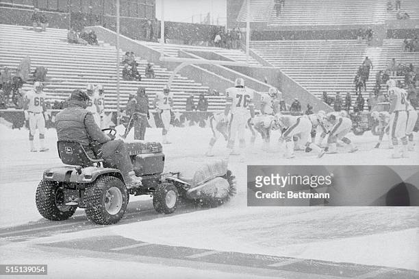 Foxboro, Mass.: Mark Henderson operator of the power brush sweeps snow off the playing field at Schaefer Stadium during snow storm, as the Dolphins...