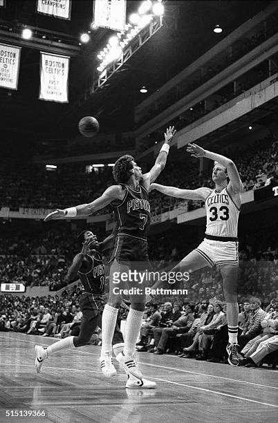 Celtics' Larry Bird passes off as he is guarded closely by Pistons' Kelly Tripucka and Isiah Thomas during 2nd quarter action at Boston Garden, 4/10....