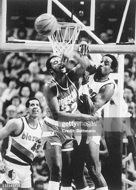 Forward Joe Bryant of the Houston Rockets swats away a shot from Portland Trailblazers' forward Kenny Carr as Portland's center Wayne Cooper looks on...