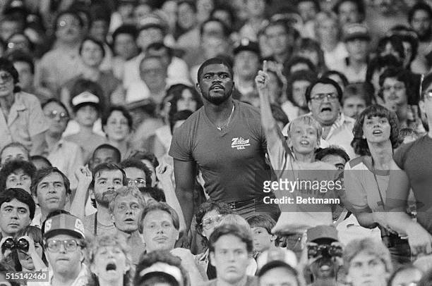 New York Giant's linebacker Lawrence Taylor stands amongst the spectators at Giant stadium to get a better view of his team in action during the...