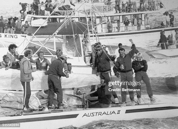 Newport, R.I.: Happy crew of Australia II is saluted by spectators as they were towed to dock are after defeating the American 12-meter yacht Liberty...