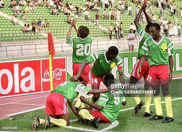 Cameroon's forward Roger Milla is congratulated by his teammates Emile Mbouh Mbouh and Stephen Tataw after scoring a goal as Cyrille Makananaky ,...