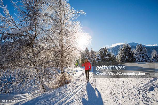 woman cross country skiing on sunny day. - nordic skiing event stock pictures, royalty-free photos & images