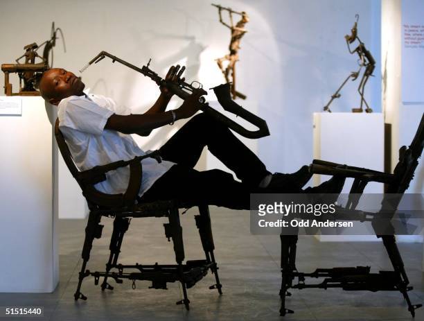 Mozambican sculptor Goncalo Mabunda poses 17 January 2002 at the OXO gallery in London with his saxophone made out of material from an AK 47 assault...
