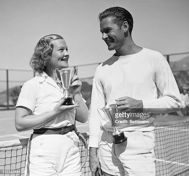 After Winning Mixed Doubles. Irene Biller and her partner, Errol Flynn, with the trophies they won in taking the mixed doubles at the Movie Tennis...