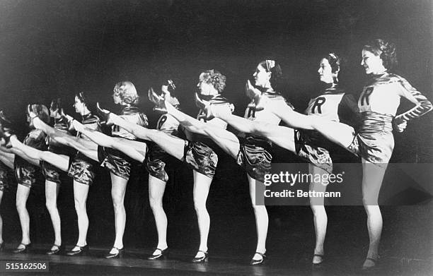New York, New York: The Rockettes on stage at Radio city Music Hall with the letter "R" on their costumes and legs raised for their classic chorus...