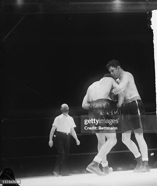 James Braddock , his face bruised and swollen, hangs onto Joe Louis in a clinch in the seventh round of their title bout in Chicago.