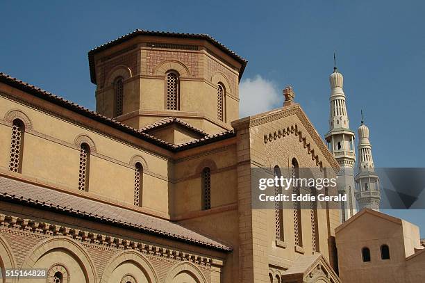 view of the catholic church of saint francois de la salleh with a mosque minaret in background in the city of ismailia egypt - egypt mosque stock pictures, royalty-free photos & images