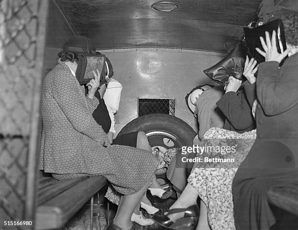 Women found in an "Institute of Massage" during a raid on the establishment hide their faces in the back of a police wagon as they wait to be taken...