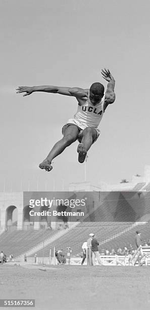 Midair action shot of UCLA student Jackie Robinson winning an event at a track meet at the Los Angeles Coliseum.