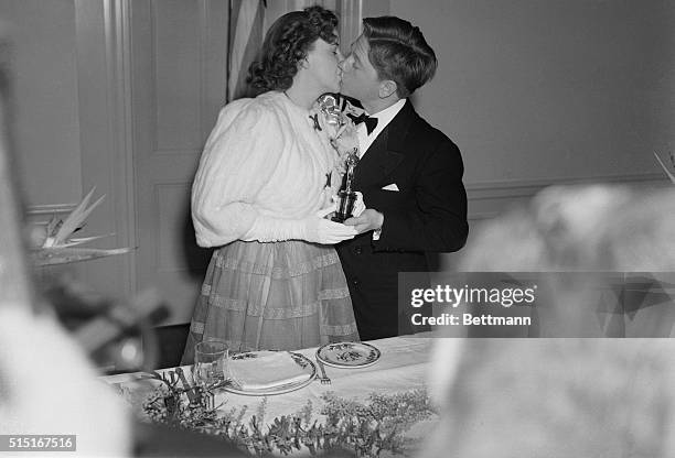 Mickey Rooney, irrepressible young film star, simultaneously presents a kiss and a special Academy Award to Judy Garland, who was adjudged the...