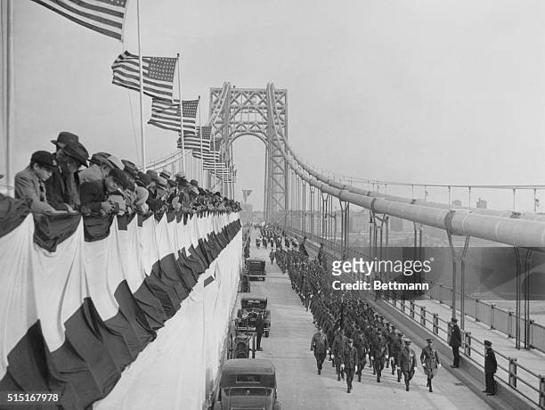 Police officers march beneath American flags during the opening ceremonies for the George Washington Bridge in New York City, October 24, 1931.