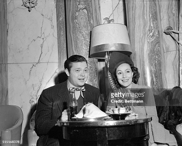 The unpredictable Orson Welles has a soft drink as lovely Dolores Del Rio has a spot of coffee at their meeting with the press in the Ambassador...
