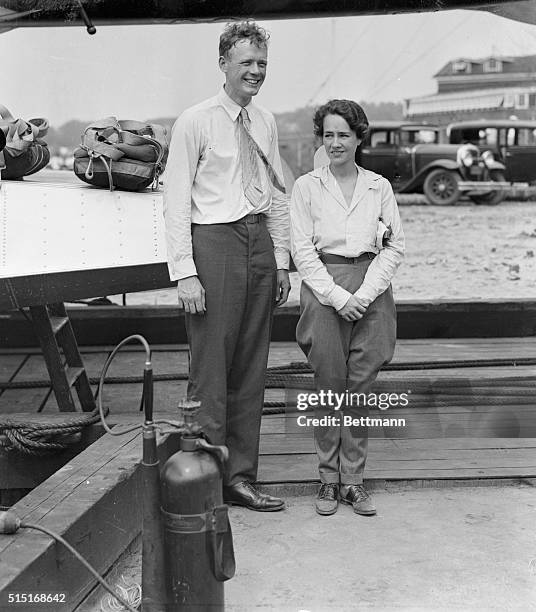 Photo shows Colonel and Mrs. Charles A. Lindbergh posing smilingly for the photographers just prior to their hop off form the College Point Airport...