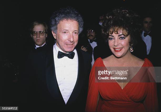 New York: Liz Taylor is radiant in red at the "Night of 100 Stars" Actors Fund benefit 2/14. Her attentive escort for the evening is producer Zev...