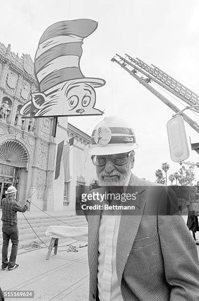 San Diego: Theodor Seuss Geisel, "Dr. Seuss", stands by as workmen raise a giant Cat in the Hat billboard to the roof of the San Diego Museum of Art...