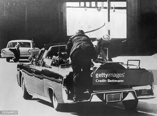 Dallas, TX: Assassination of President Kennedy, First Lady Jacqueline Kennedy leans over dying President as a Secret Service man climbs on back of...