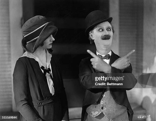 Ben Turpin , American comedic actor, giving a woman directions by crossing his eyes and pointing his hands in different directions. Undated movie...