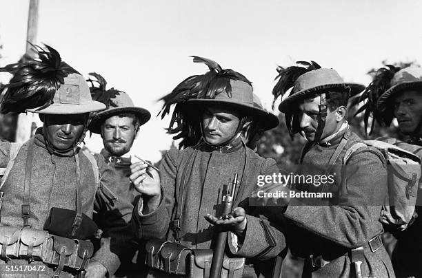 Portrait of Italian Bersagliere, in plumed hats, examining aero-darts dropped by Austrian airmen. Undated photograph.