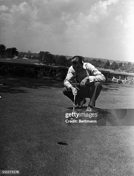 Ben Hogan, professional golfer, kneels down to line up what will hopefully be his final putt for third hole in the PGA tournament.