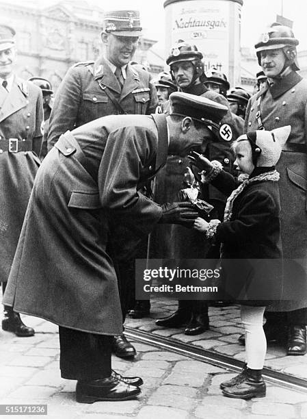 Arriving in Vienna to personally conduct the plebiscite campaign, Dr. Josef Goebbels, German Propaganda Minister, was met by this little girl, who...