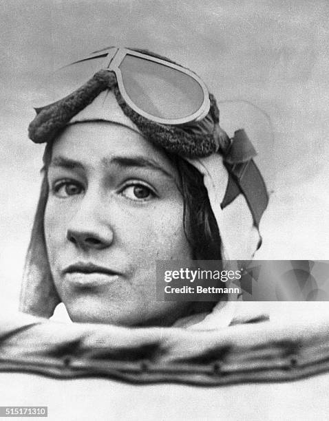 Fine closeup of Mrs. Anne Morrow Lindbergh, as she appeared in flying helmet in her husband's plane en route to California from this city. She is...