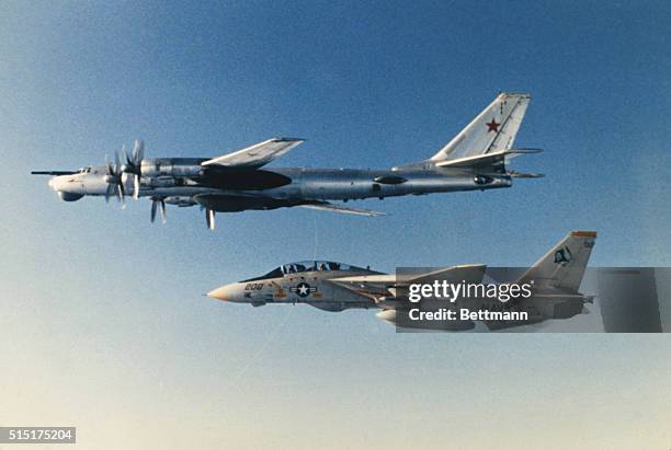 Photo of a Russian TU-95 being led by United States F-14 in the sky.