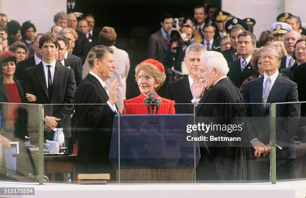 President-elect Ronald Reagan takes the oath of office during inauguration ceremonies in Washington, DC. His wife, Nancy, is holding the Bible and...