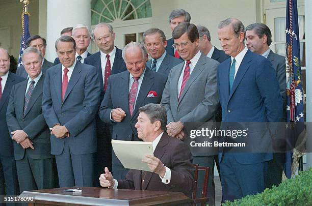 Washington, DC: President Reagan holds up the bill intended to wipe out the deficit in six years after signing it, September 29. With him from left...