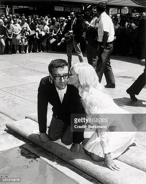 Actor Peter Sellers plants his hands and feet in the forecourt of Hollywood's Grauman's Chinese Theatre as bride Britt Ekland gives him a kiss....