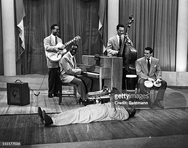 Nat King Cole , American musician with his trio on "Harlem House" a variety show. Cole is at piano, on piano floor is Timmy Rogers, master of...