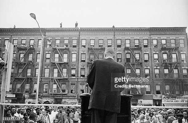 Police look down from the top of a nearby building as Malcolm X addresses a Black Muslim rally in Harlem. Police covered this meeting and a rally...