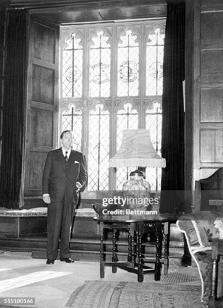 Jean Paul Getty poses before one of the windows of Sutton Place, the Duke of Sutherland's estate, before buying it.