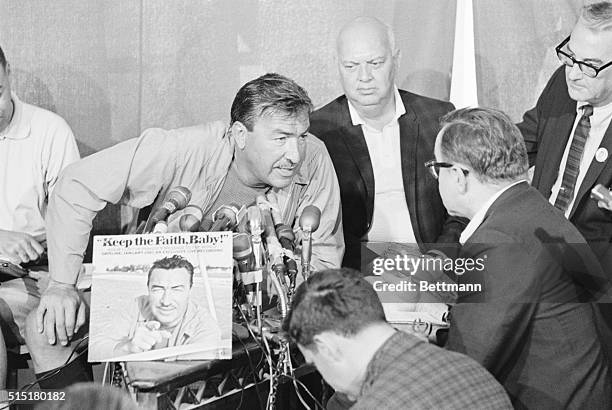 Bimini, Bahamas: Leaning over a battery of microphones, congressman Adam Clayton Powell answers a reporter's question during a press conference in...