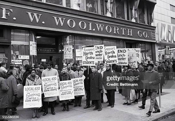 New York, NY: Placard-carrying demonstrators mass in front of a Woolworth store in Harlem here Feb. 13 to protest lunch counter discrimination...