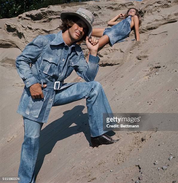 Robert Chernin uses a bleached blue denim look for a safari style jacket and matching pants, accessorized with a full belt, four flapped pockets and...