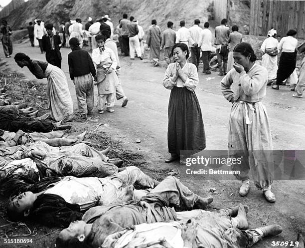 Hamhung, Korea: Korean women weep as they identify their men who were killed by the Communist-led North Korean forces. The victims were forced into...