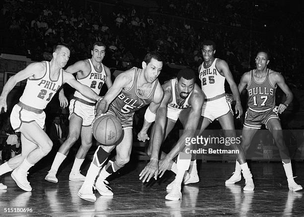 Philadelphia, PA- Chicago's Guy Rogers drives pst lunging 76er Wilt Chamberlain after finding quarters under the basket too cramped to shoot. 76er...