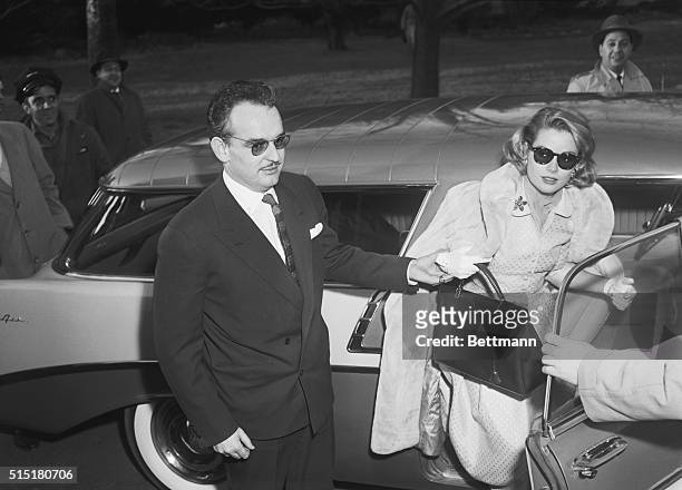 Prince Rainier III of Monaco helping his fiancee Grace Kelly out of a car. Kelly holds the style of Hermes handbag that was named after her.