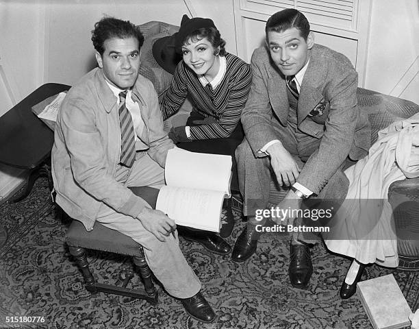 Left to right: Frank Capra, Claudette Colbert and Clark Gable seated.