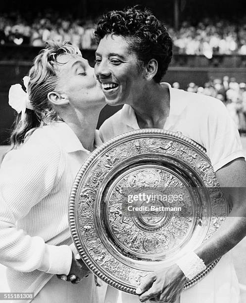 Darlene Hard kisses Althea Gibson after Gibson defeated her 6-3, 6-3, in the finals of the women's singles tennis championship at Wimbledon. Gibson...