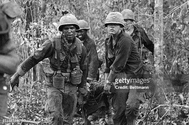 Tay Ninh, South Vietnam- Using a shirt as a stretcher, GI's carry a wounded soldier from the jungle thicket after heavy fighting near the Cambodian...