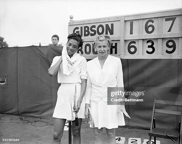 Forest Hills, NY- Wimbledon champion Louise Brough of Beverly Hills, California poses with Althea Gibson of New York, in front of the scoreboard...