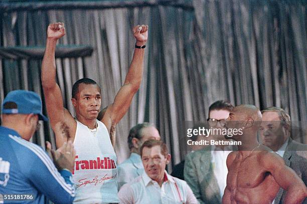 Las Vegas, NV- Champion Marvin Hagler looks on as Sugar Ray Leonard raises his arms while on the scale during a weigh-in for the title fight.